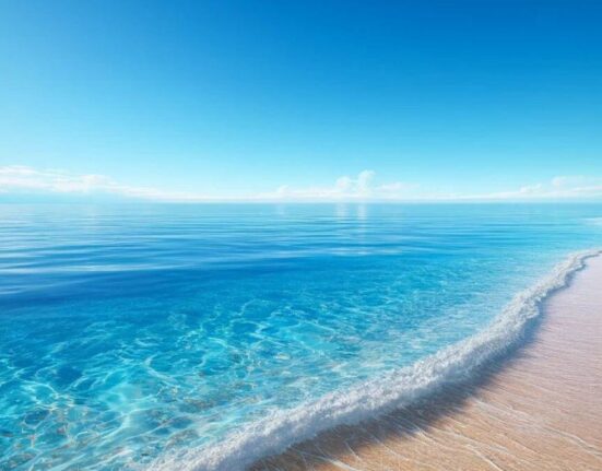 A pristine beach with crystal clear water under a bright blue sky, creating a serene and inviting scene.