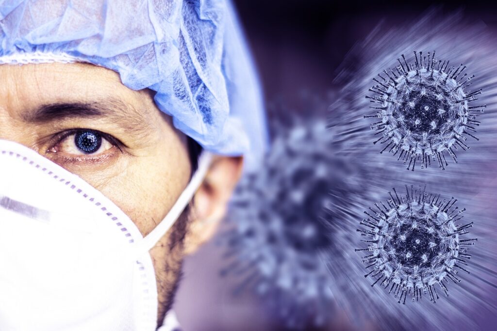 A close-up of a healthcare worker wearing a surgical mask and cap, with illustrations of the COVID-19 virus in the background.