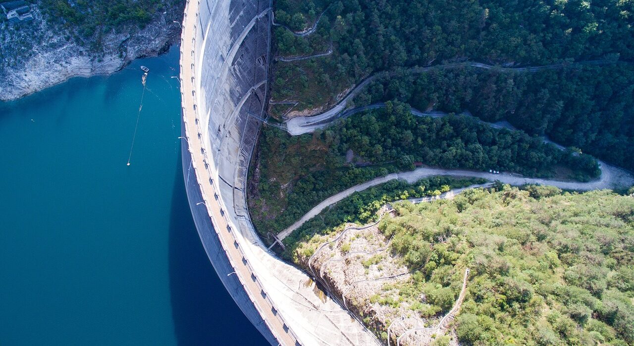 Aerial view of a large dam surrounded by water and forest.